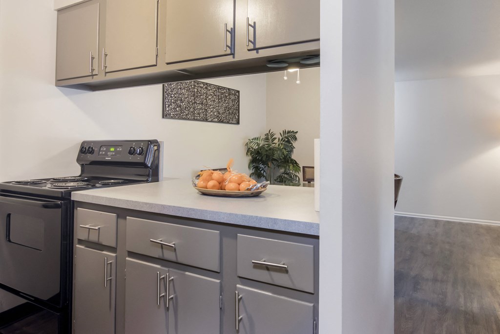 a kitchen with white cabinets and a bowl of fruit on the counter
