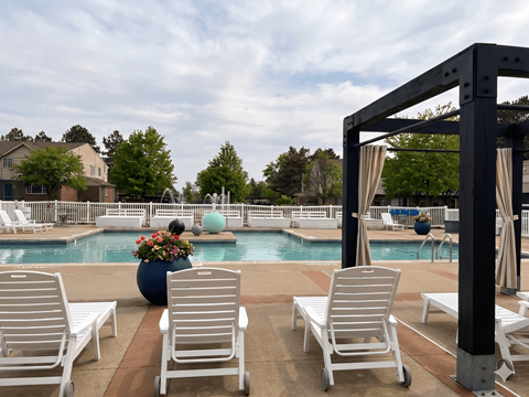 A poolside area with white chairs and a black pergola.
