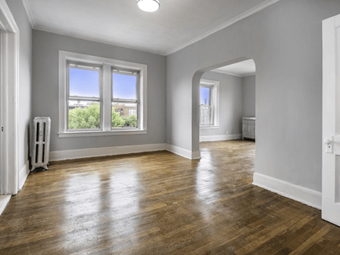 an empty living room with a hardwood floor and two windows