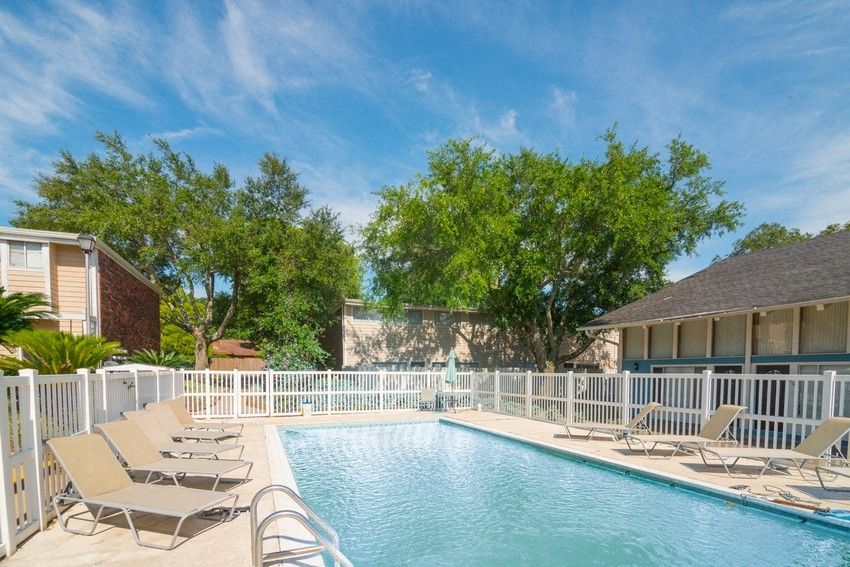 Outdoor pool with lounge chairs and white picket fence.