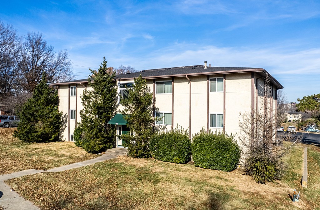 an apartment building with bushes and trees in front of it
