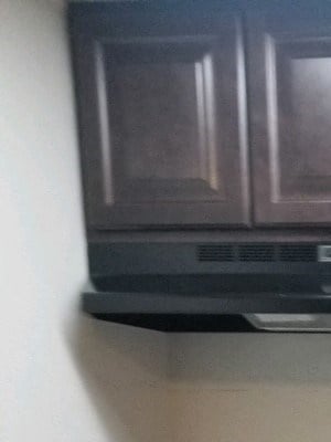 Kitchen with hardwood like flooring, a black stove, stainless steal sink, white countertops, and dark brown cabinets. - Photo Gallery 4