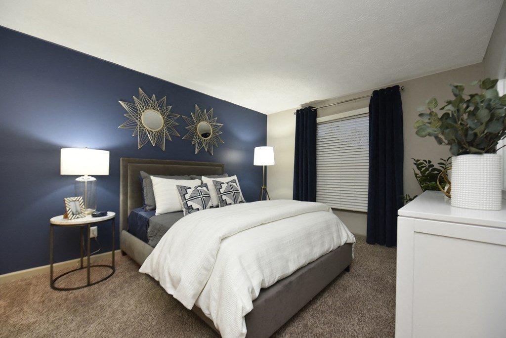 a bedroom with a blue accent wall and a white bed