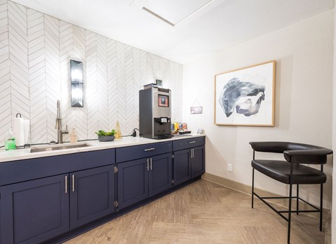 A kitchen with dark blue cabinets and a black chair.
