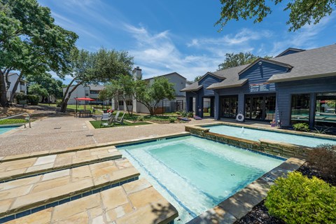 A swimming pool surrounded by a stone patio and trees.