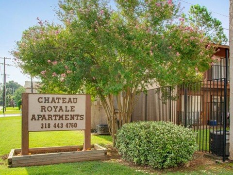 a chateau royale apartments sign in front of a tree