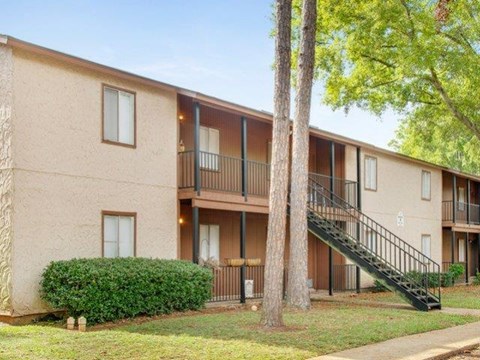 the exterior of an apartment building with trees and a staircase