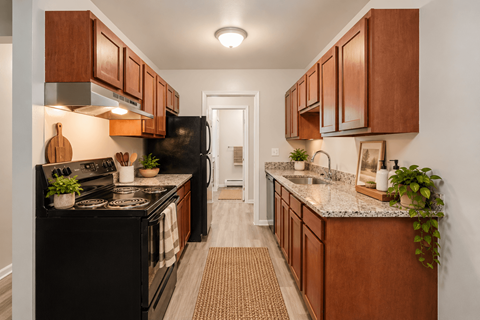 A kitchen with brown cabinets and a black refrigerator.