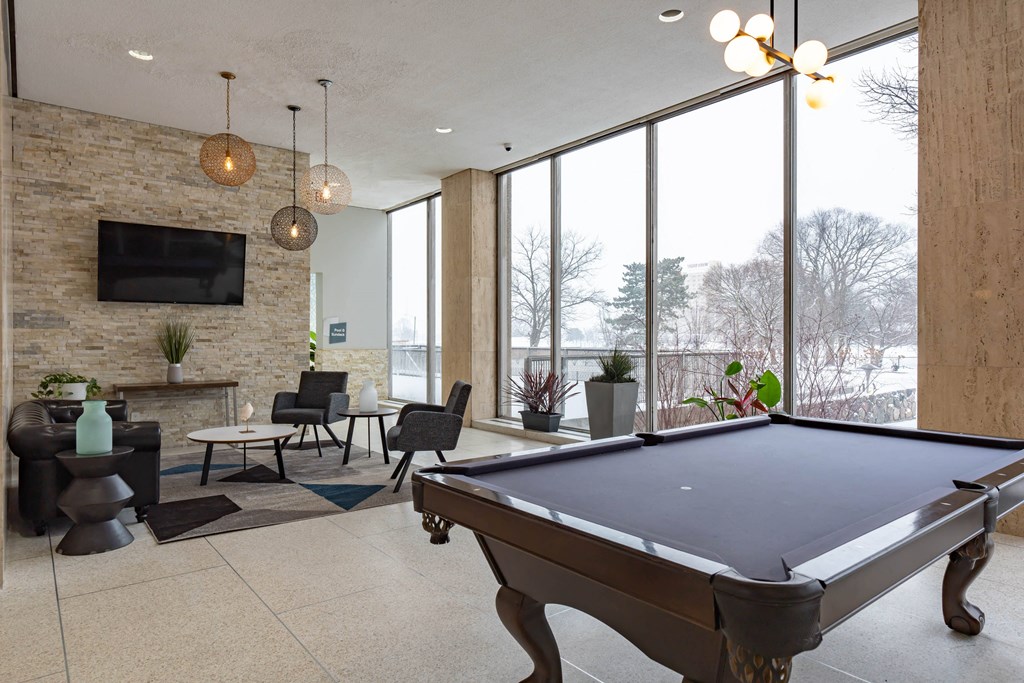 a pool table in the lobby of a building with large windows