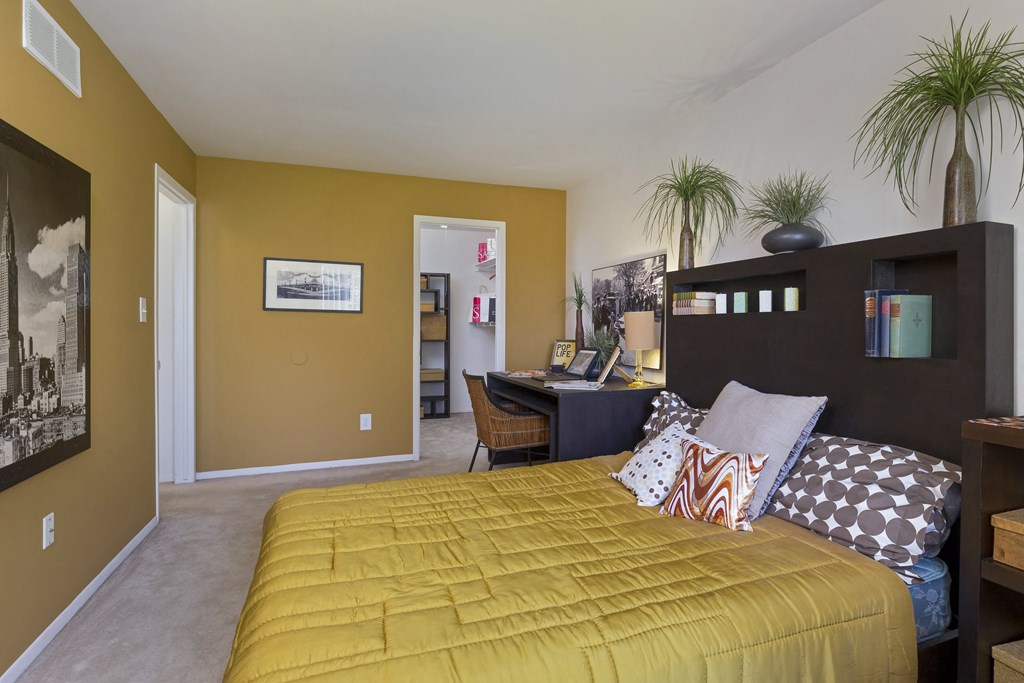 a bedroom with a yellow bed and a desk with a computer at Village Club of Rochester Hills, Shelby Township