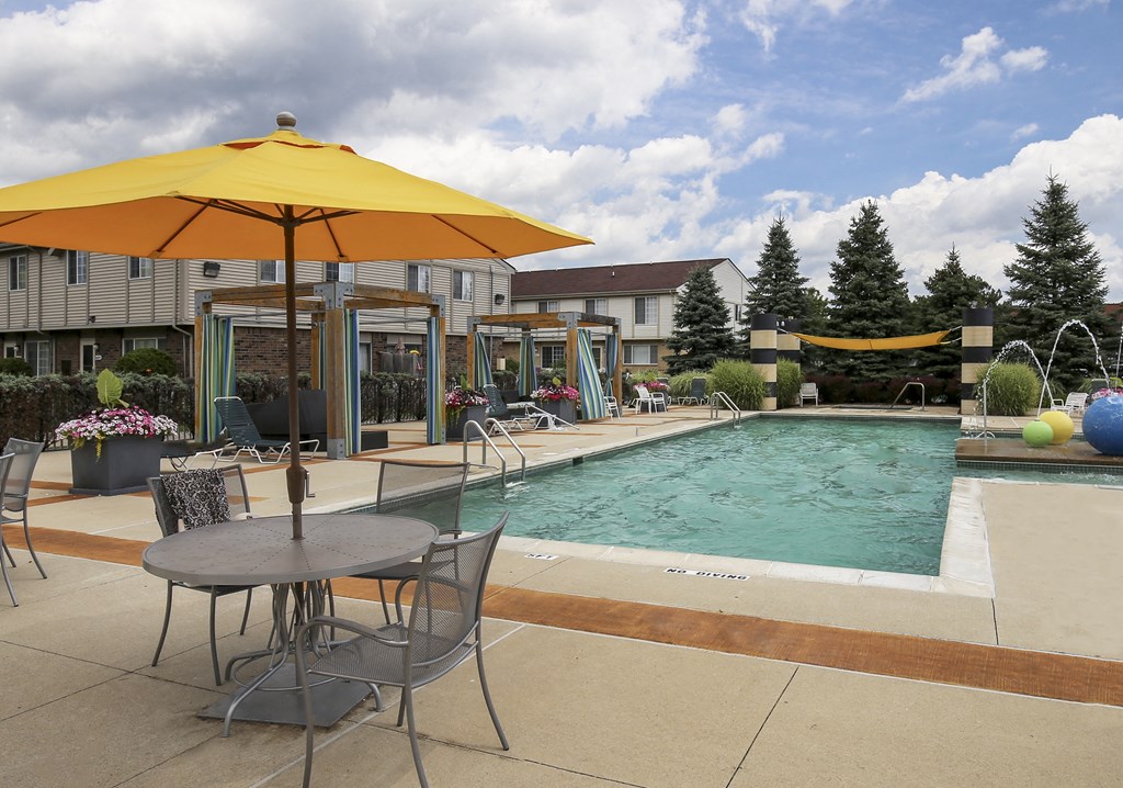 our apartments have a pool and patio with chairs and umbrellas at Village Club of Rochester Hills, Shelby Township, 48317