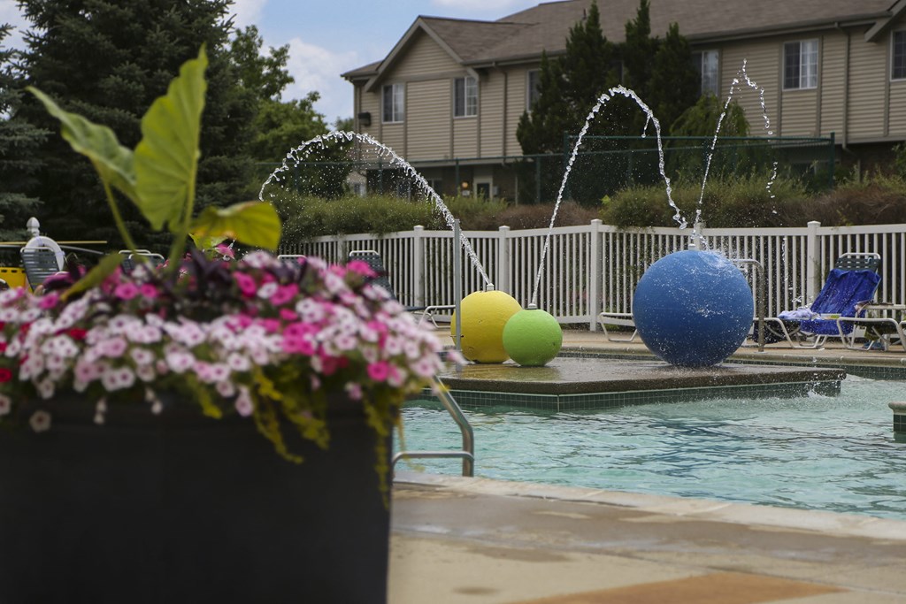 a swimming pool with water sprinklers and a house in the background at Village Club of Rochester Hills, Michigan, 48317