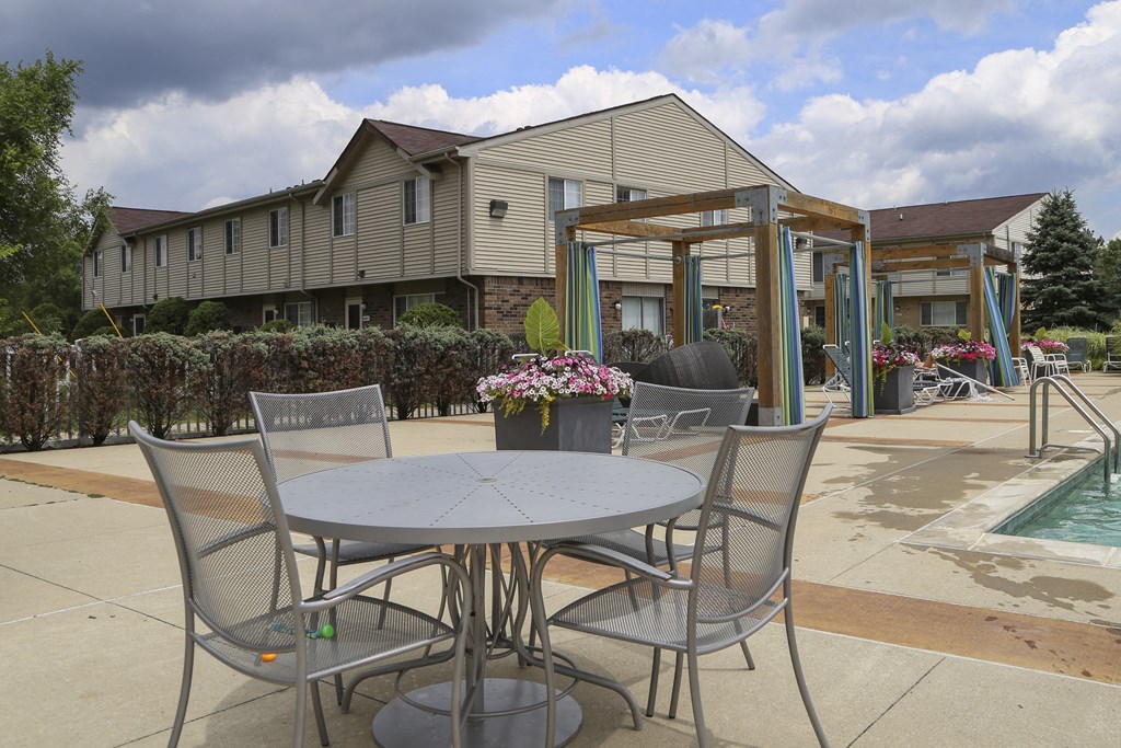 a patio with a table and chairs next to a swimming pool at Village Club of Rochester Hills, Shelby Township Michigan
