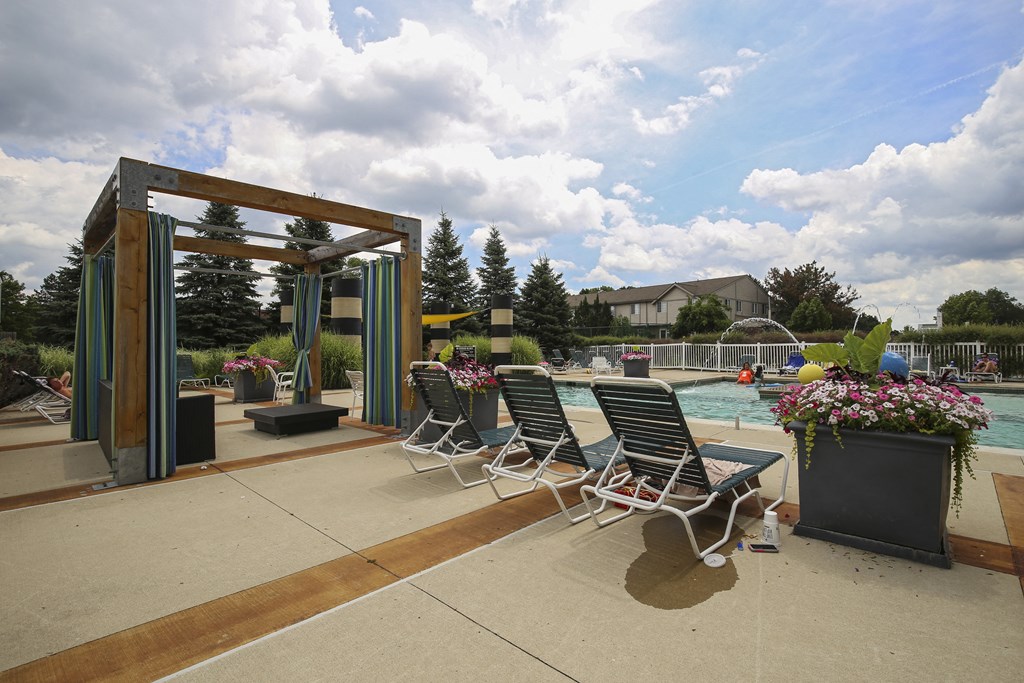 a pool with lounge chairs and a water fountain at Village Club of Rochester Hills, Shelby Township, MI 48317