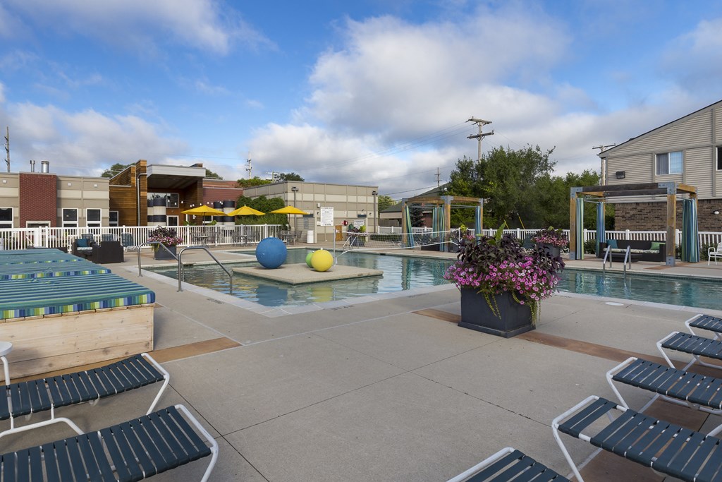 a pool with lounge chairs around it and a building with umbrellas at Village Club of Rochester Hills, Michigan, 48317