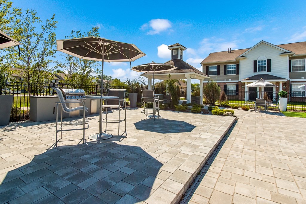 a patio with chairs and umbrellas in front of a house