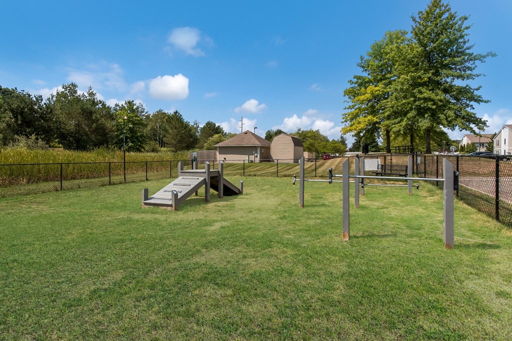 a fenced in dog park with a ramp and a fence