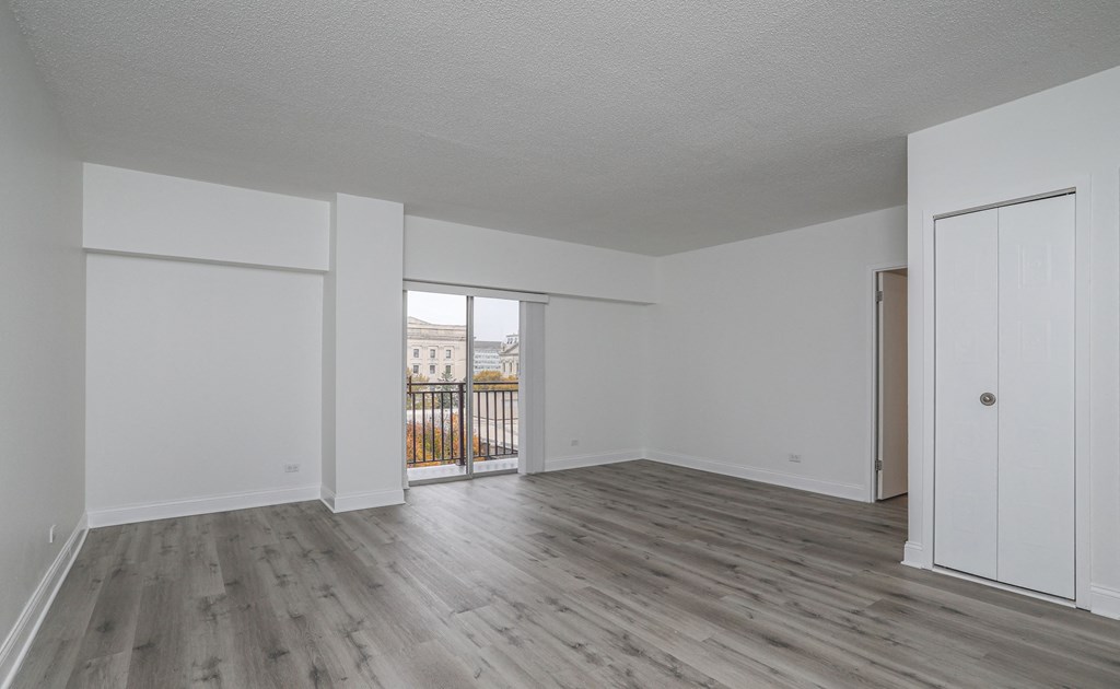 an empty living room with wood flooring and a balcony