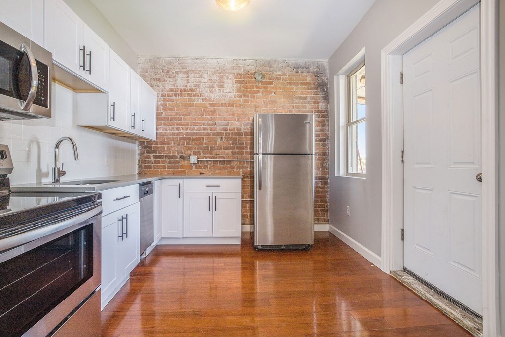 a kitchen with white cabinets and a stainless steel refrigerator