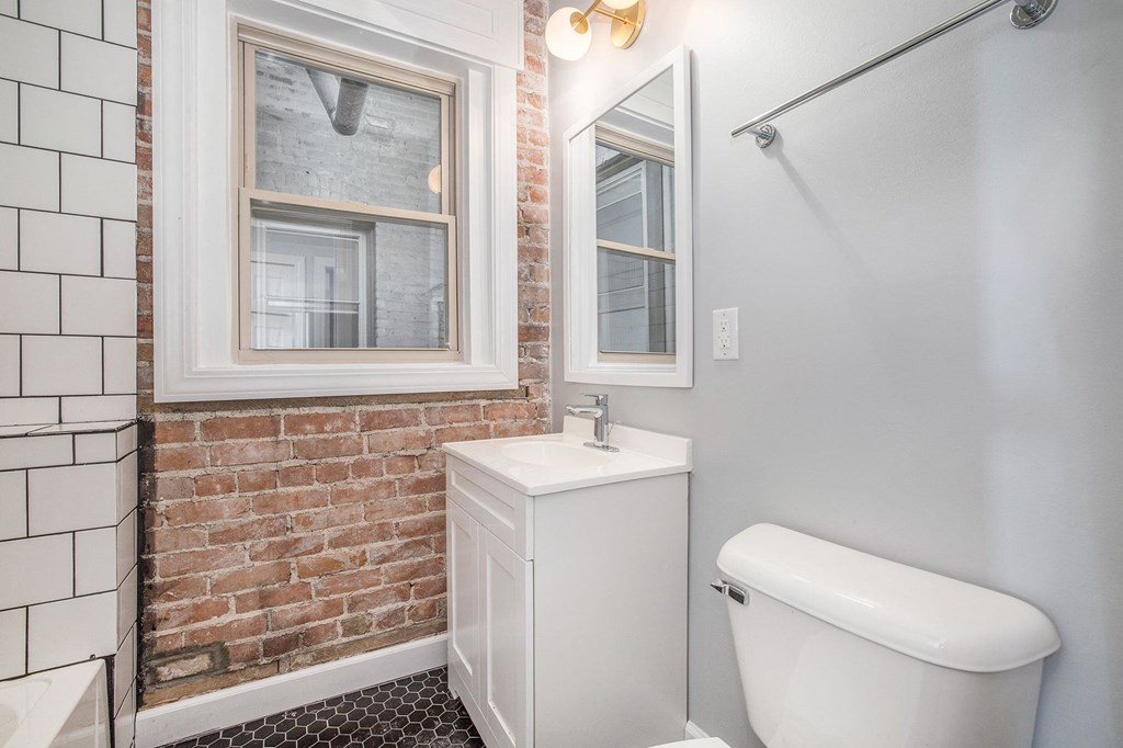 a bathroom with a brick wall and a toilet and a sink