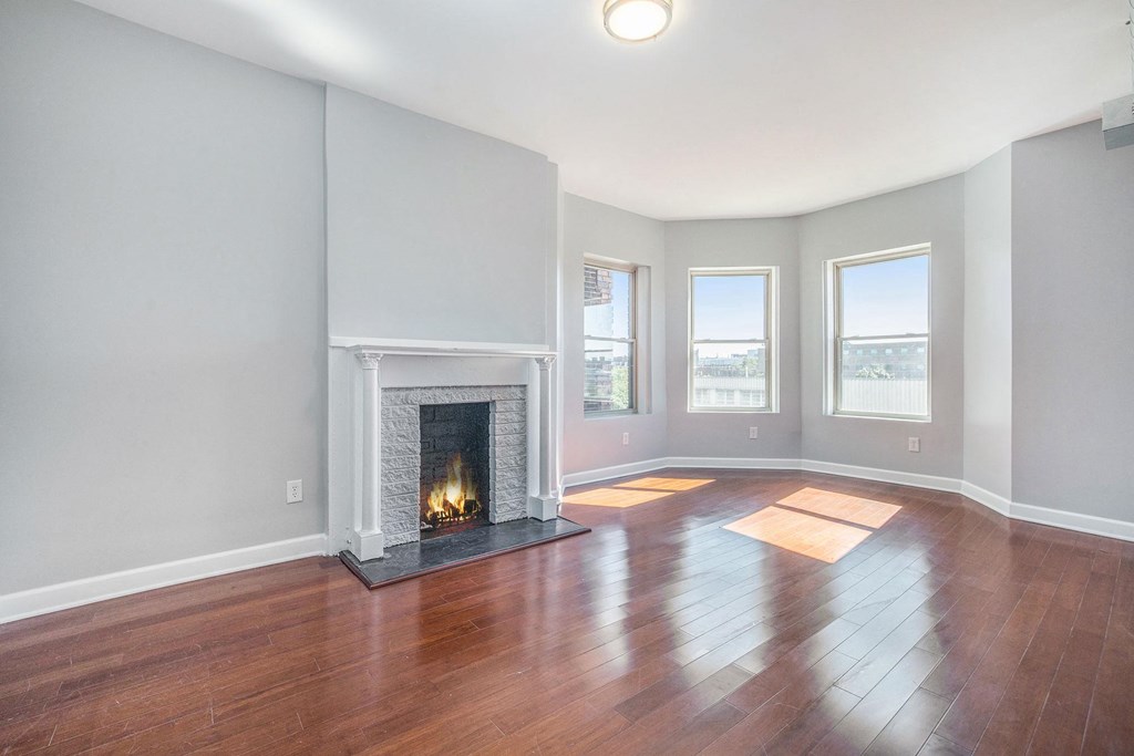 an empty living room with a fireplace and wooden floors