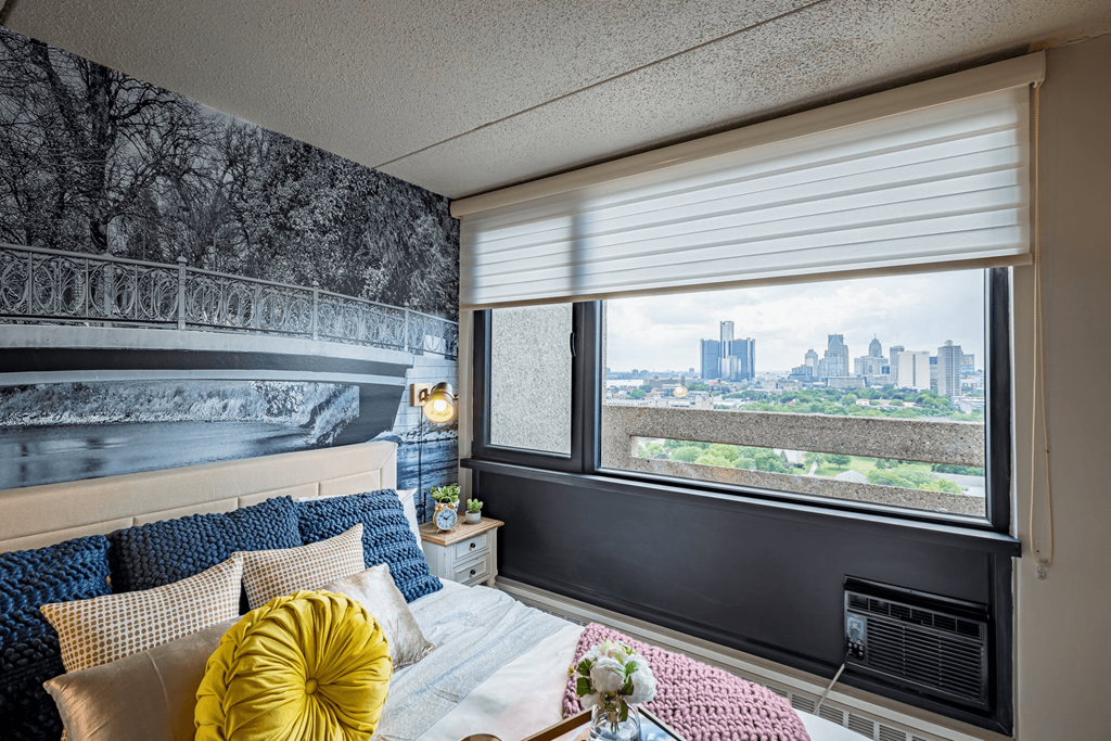 a bedroom with a bed and a window overlooking a city at City Club Apartments Lafayette Park, Detroit, Michigan