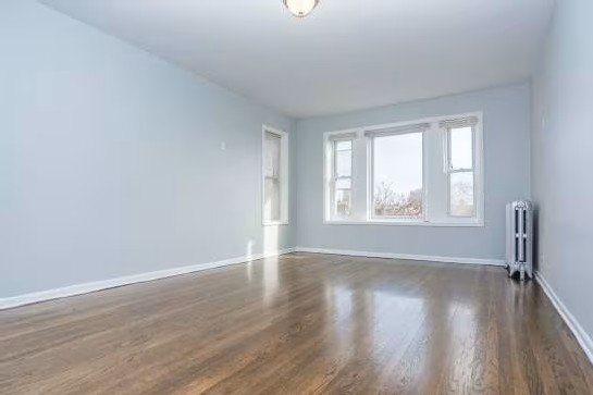 A room with wooden floors and a radiator on the wall.