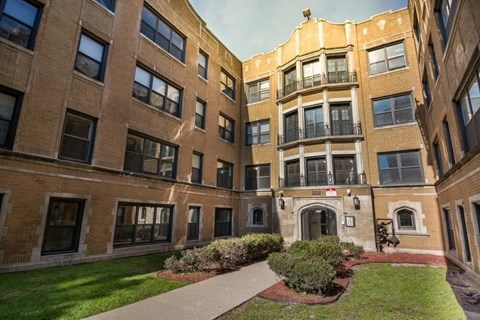 A courtyard surrounded by brick buildings with a walkway in the middle.