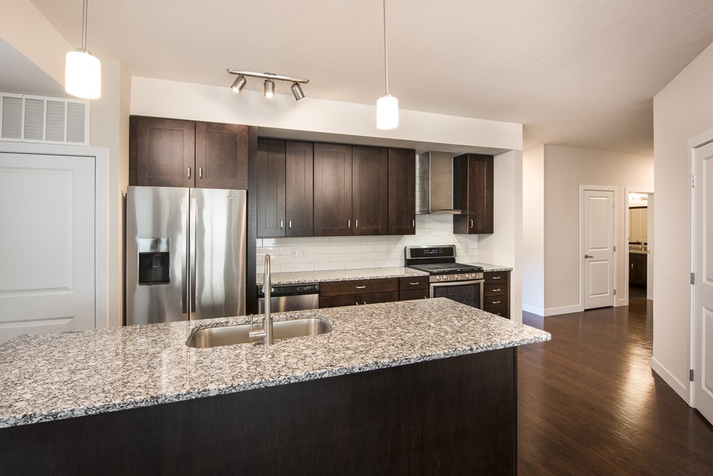 A kitchen with a granite countertop and stainless steel appliances.