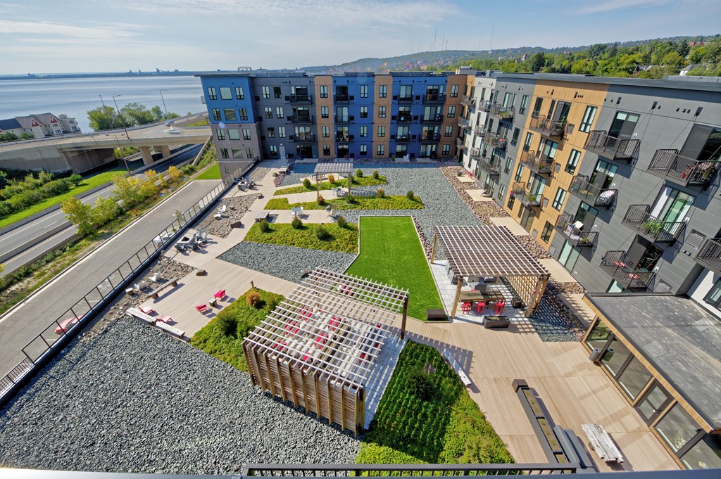 A modern apartment complex with a green courtyard and a body of water in the background.