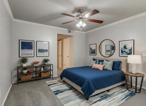 A bedroom with a blue bed and a ceiling fan.