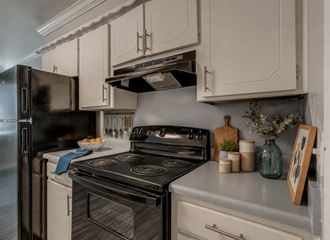 A black stove top oven sits next to a white dishwasher in a kitchen.
