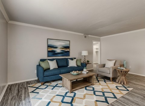 A living room with a blue couch, a coffee table, and a painting on the wall.