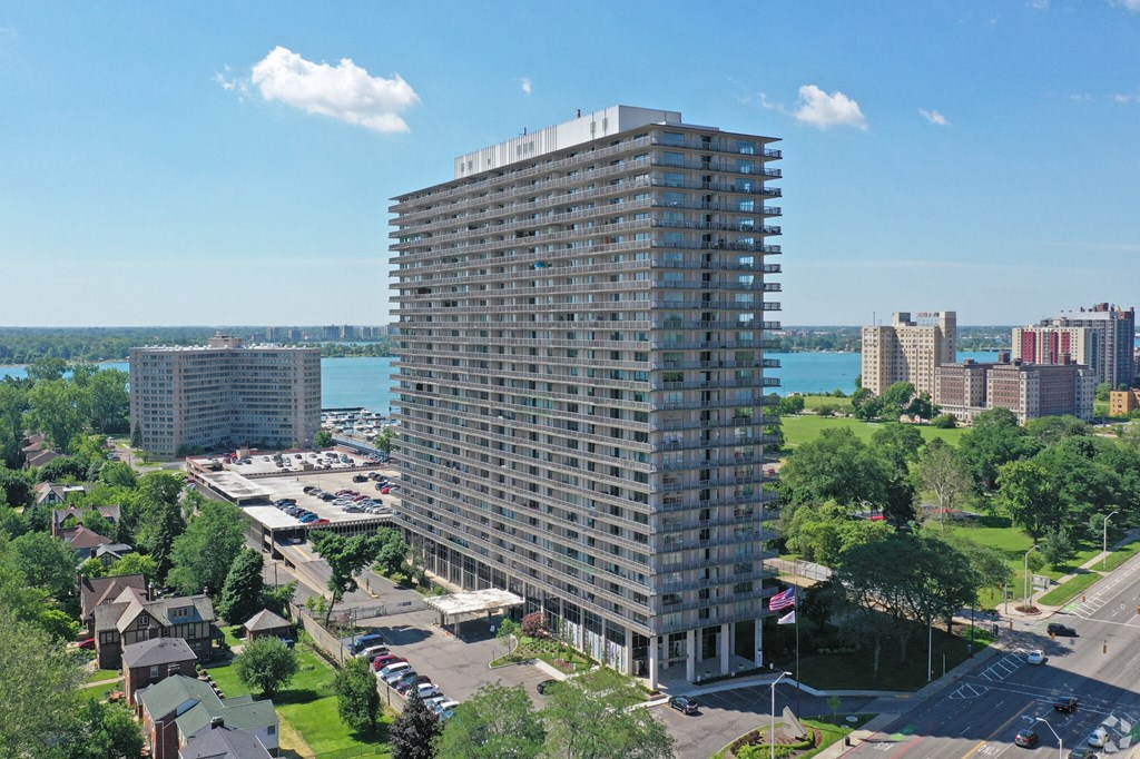 Image of exterior of building. Building stands 30 stories tall, blue skies and green trees surrounding.