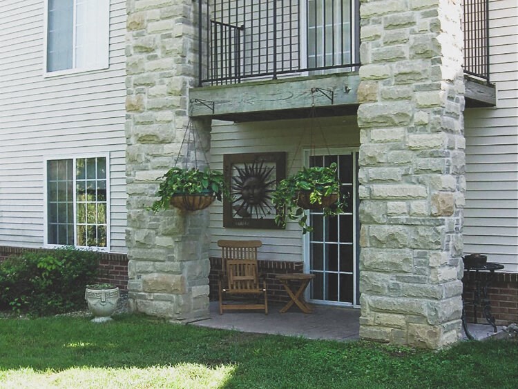 Secluded patio with hanging baskets and a table and chair at Riverwoods.