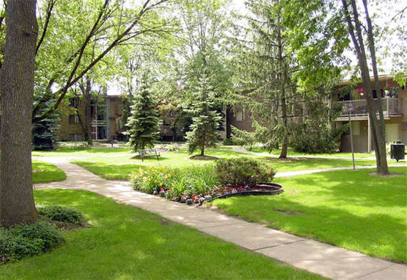 Sidewalk leading to building with landscaping and trees