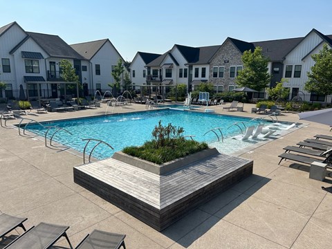 A large swimming pool surrounded by lounge chairs and a wooden deck.