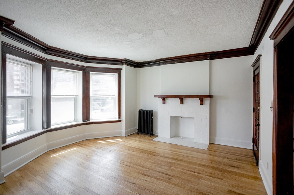 an empty living room with wood floors and a fireplace