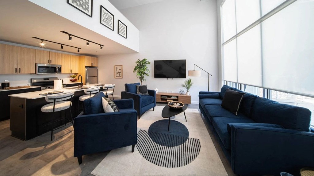 A modern living room with a kitchen area in the background at The George, Ann Arbor, MI