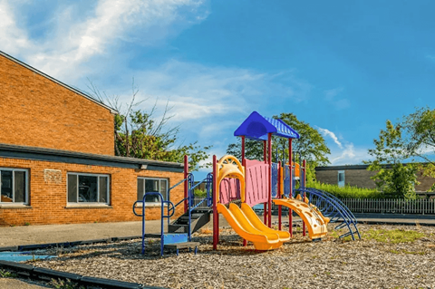A playground with a yellow slide and a blue and pink structure.