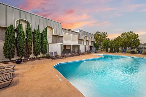 A swimming pool is surrounded by a building and trees.