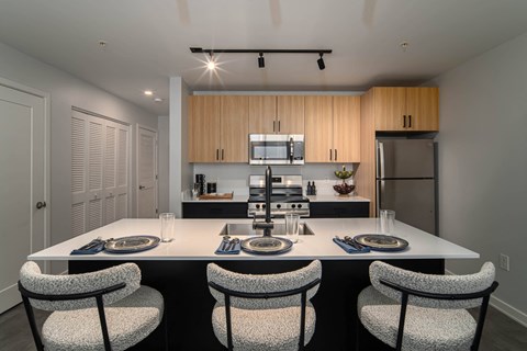 a kitchen with a large island with four chairs and a table