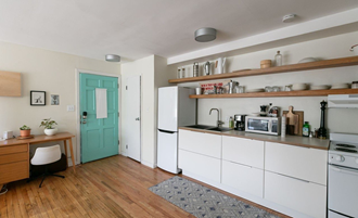 a small kitchen with white cabinets and a turquoise door