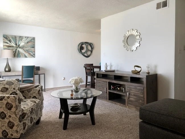 A living room with a sofa, a chair, a coffee table, and a painting on the wall.