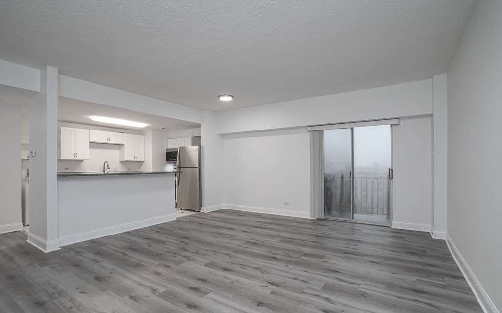 an empty living room and kitchen with a sliding glass door