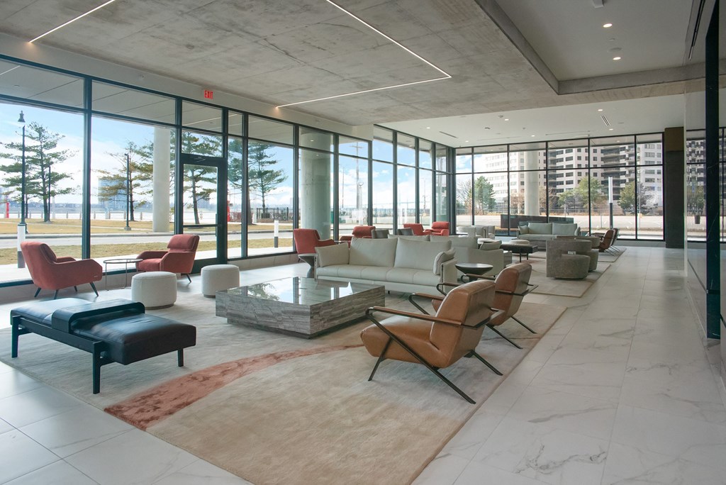 a lounge area with chairs and tables and floor to ceiling windows