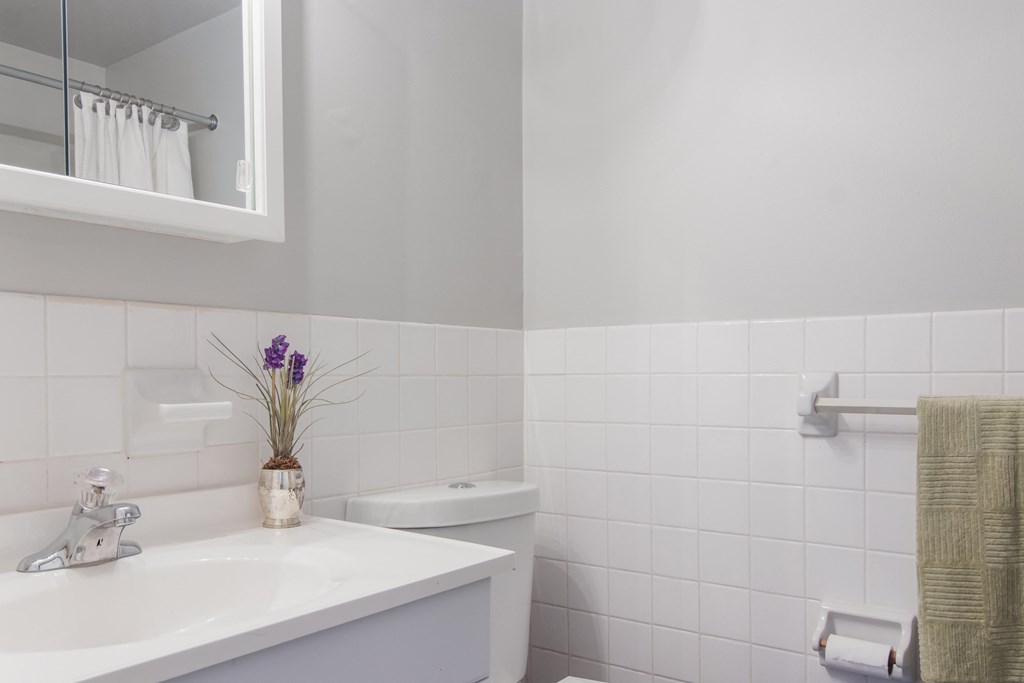 A white sink with a vase of flowers on top of it.