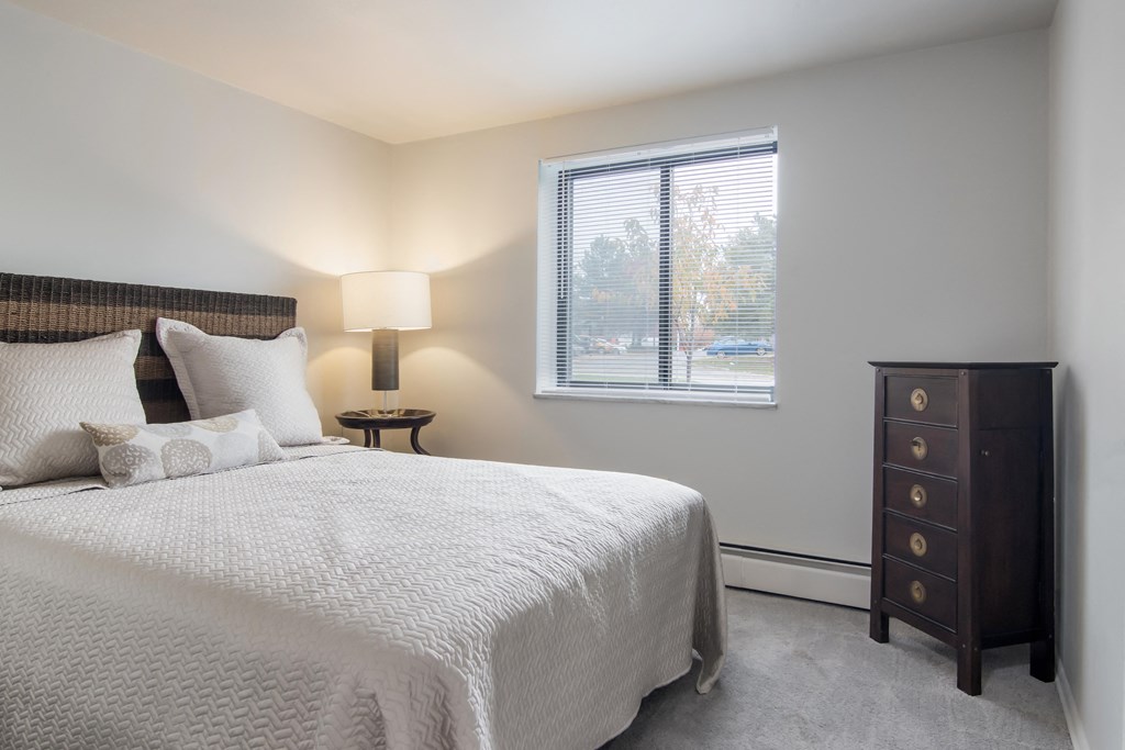 A bedroom with a large bed and a nightstand with a lamp.