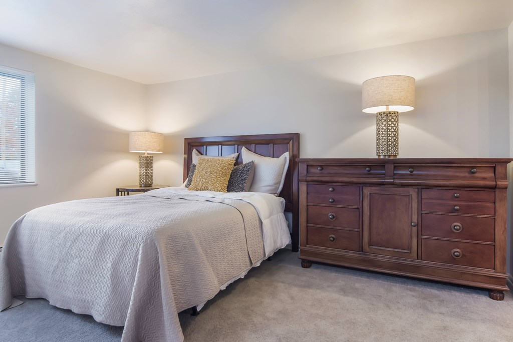 A bedroom with a bed, nightstand, and two lamps.