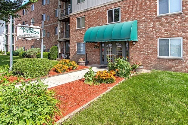 a brick building with a green awning and a green lawn